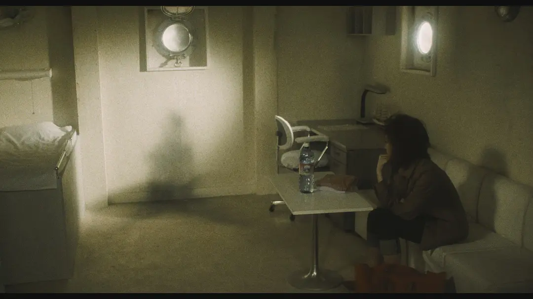 A dim room in the film Kairo; on the wall, a dark human-shaped stain where a person used to be